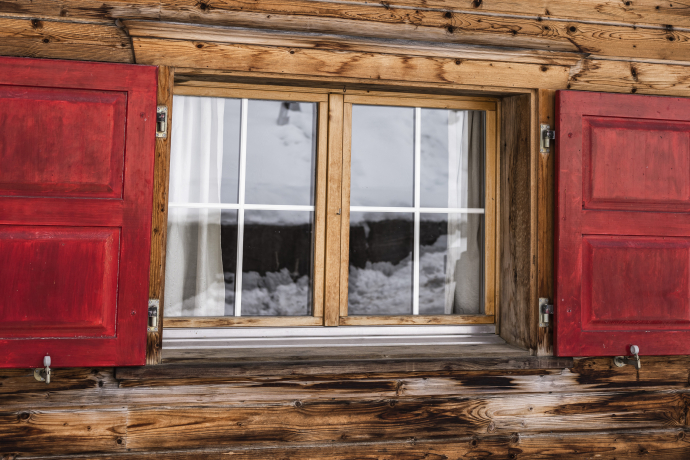 Fenster mit roten Fensterläden einer Hütte 